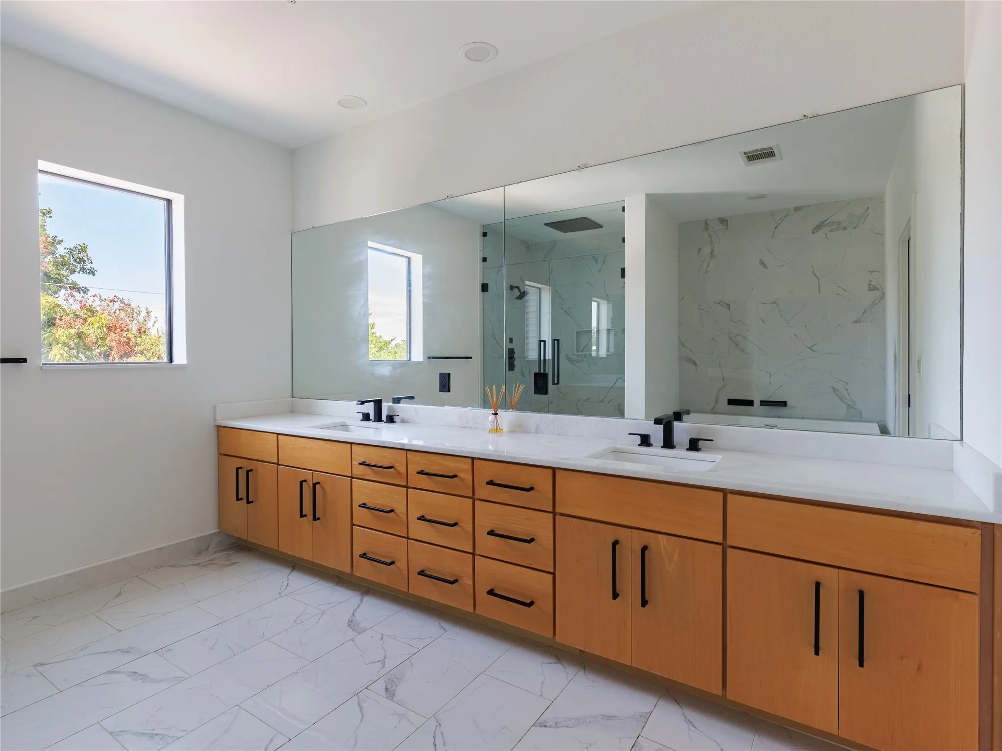 Expansive primary bath offers a spa-inspired layout with a standalone tub, spacious walk-in shower, marble surfaces, and porcelain tile flooring.