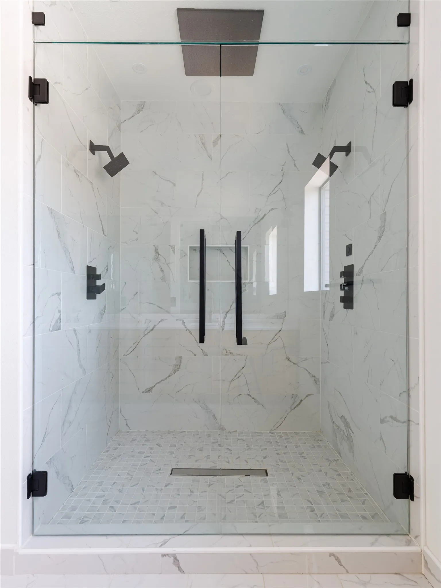 Primary bathroom featuring a freestanding tub, oversized walk-in shower, marble countertops, and porcelain tile flooring.