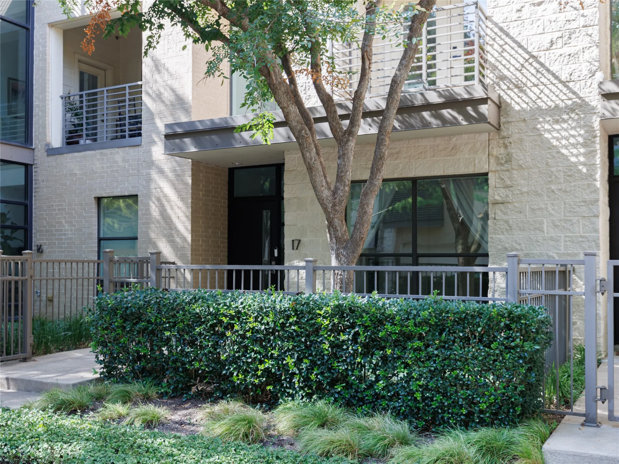 Glass doors connect the living area to a shaded outdoor balcony with peaceful treetop views.