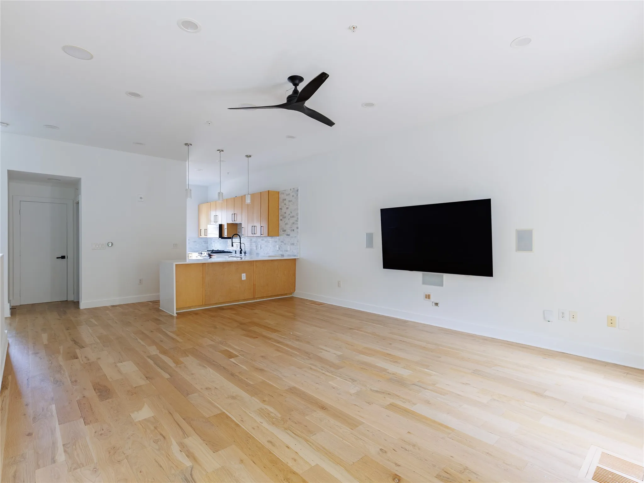 Spacious open-concept living room with hardwood floors, recessed lighting, and integrated speakers.