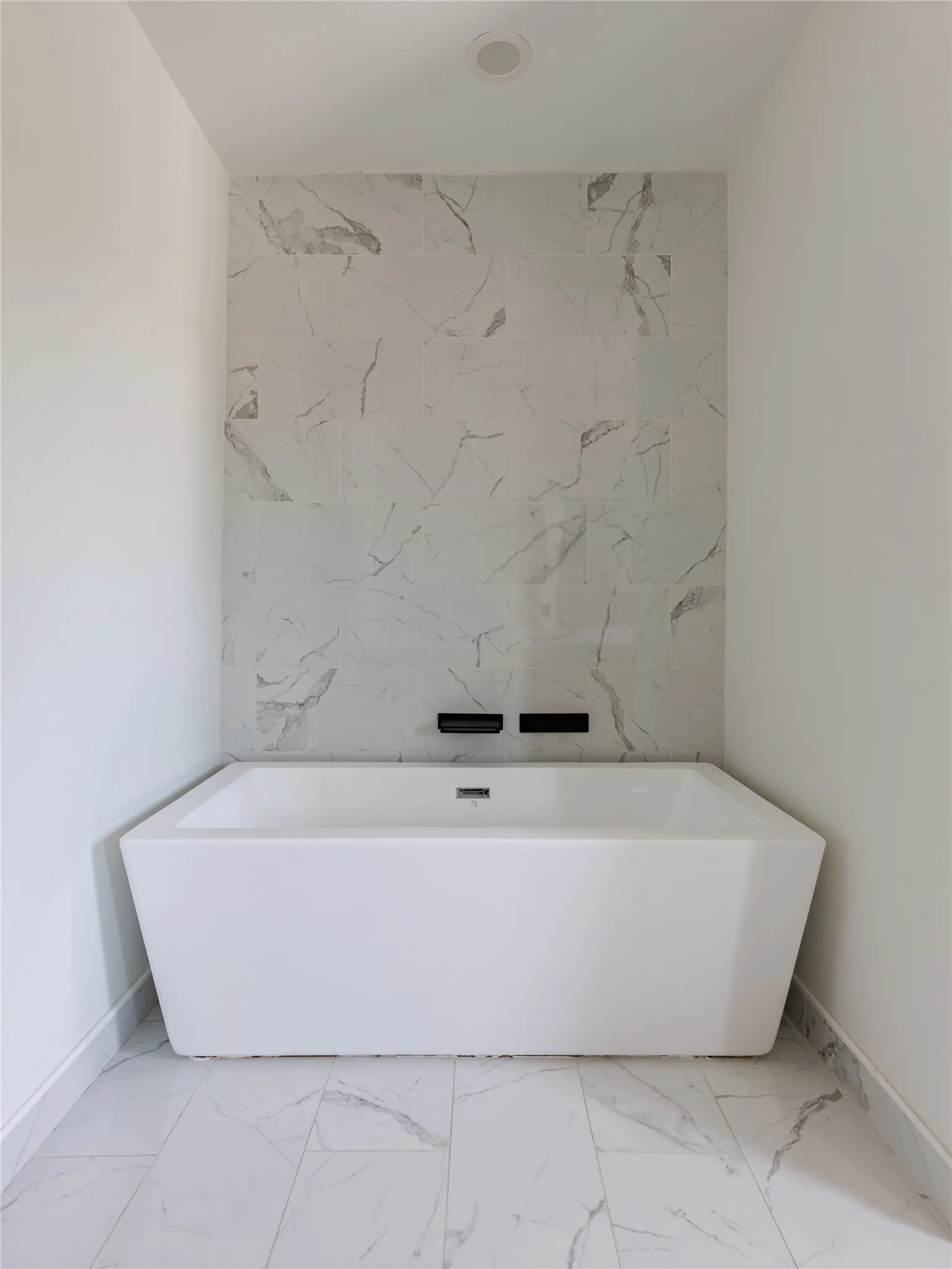Marble countertops and porcelain tile floors bring a clean, timeless finish to the spacious primary bathroom.