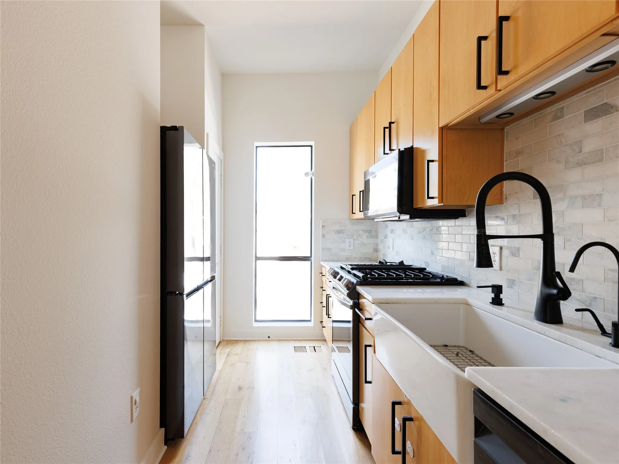 The apron-front sink creates a functional focal point beneath the matte black fixtures.