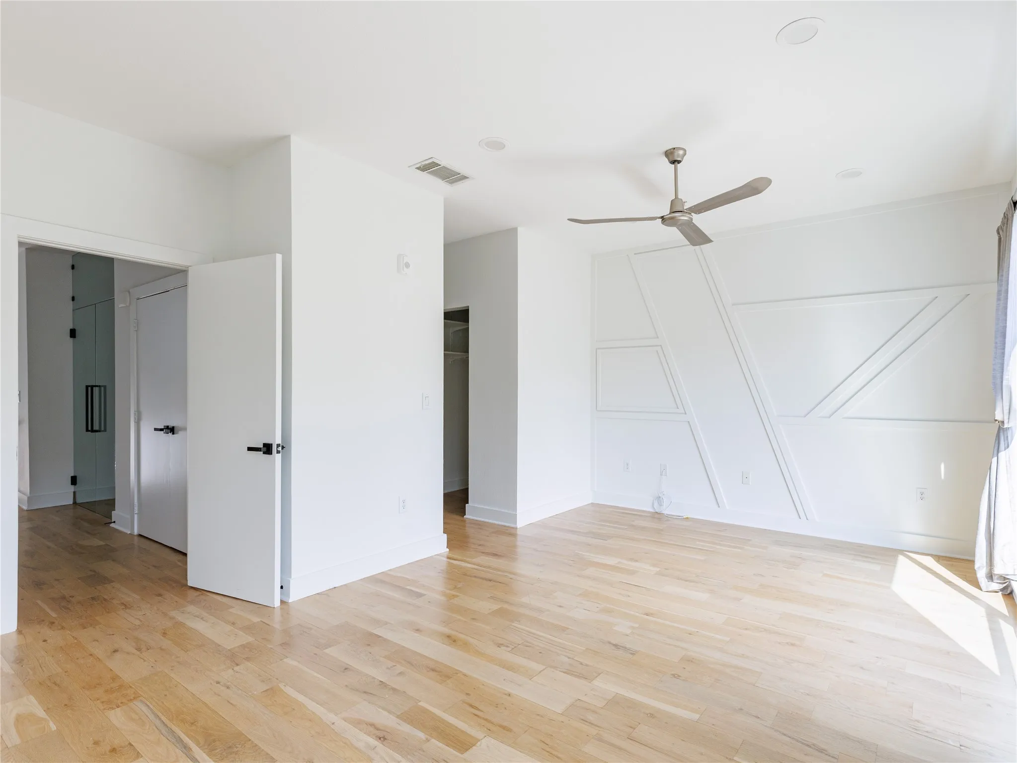Bright bedroom with large windows, warm hardwood flooring, and a flexible layout for comfortable everyday living.