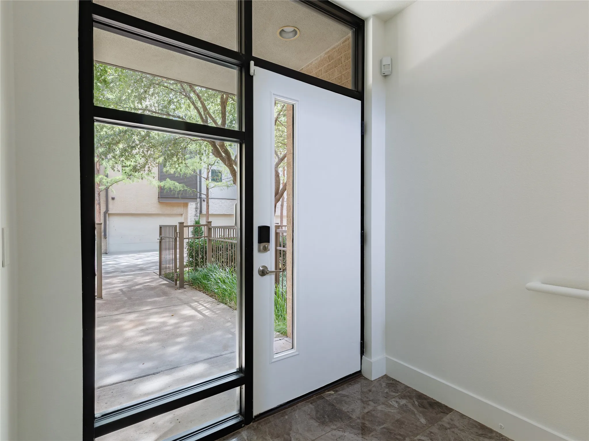 Sleek black entry door with surrounding glass panels creates a polished contemporary arrival.