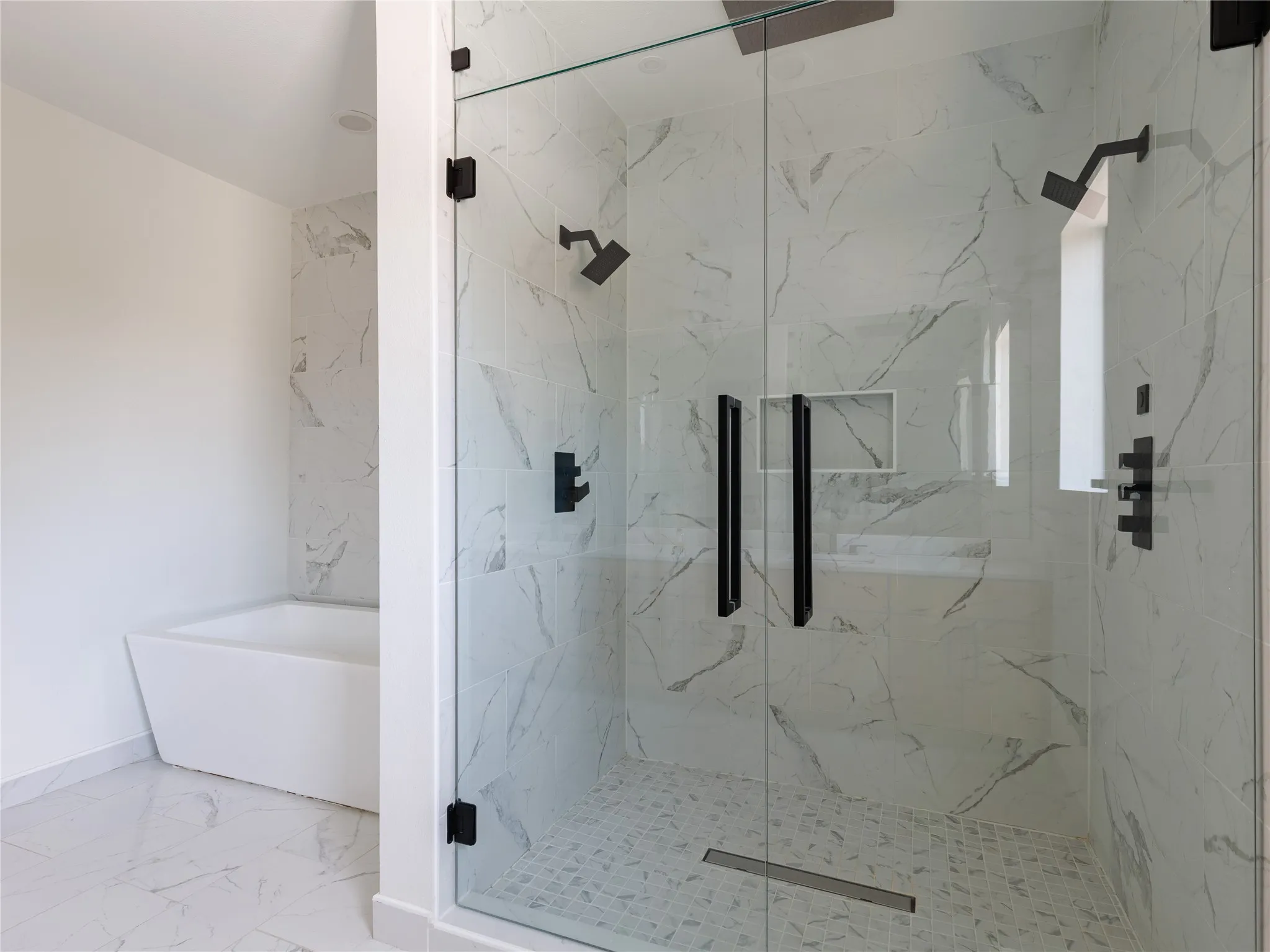 Oversized glass-enclosed shower provides a bright, open focal point within the well-appointed primary bath.
