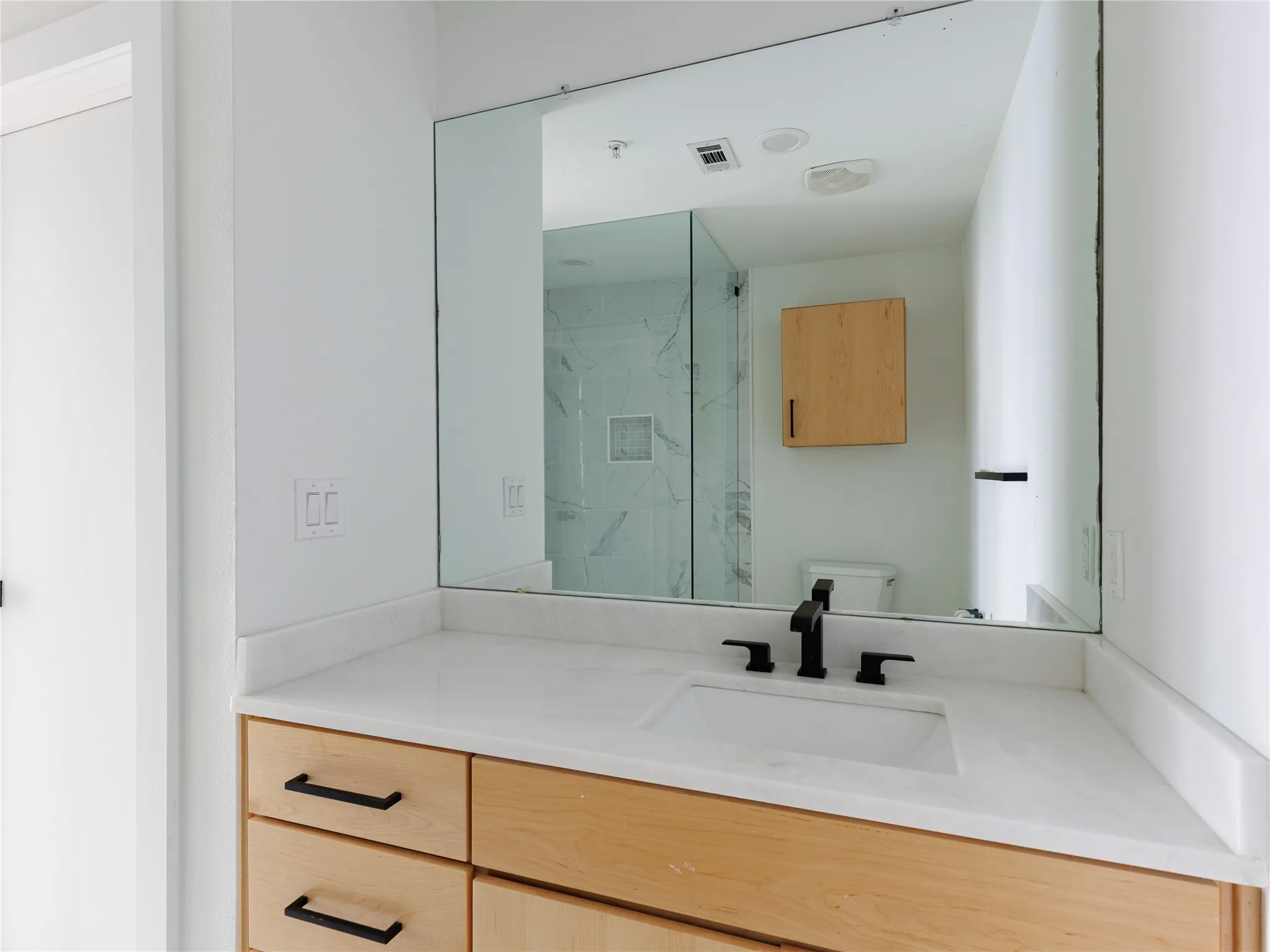 First-floor bathroom featuring marble countertops, matte black fixtures, and clean contemporary finishes.