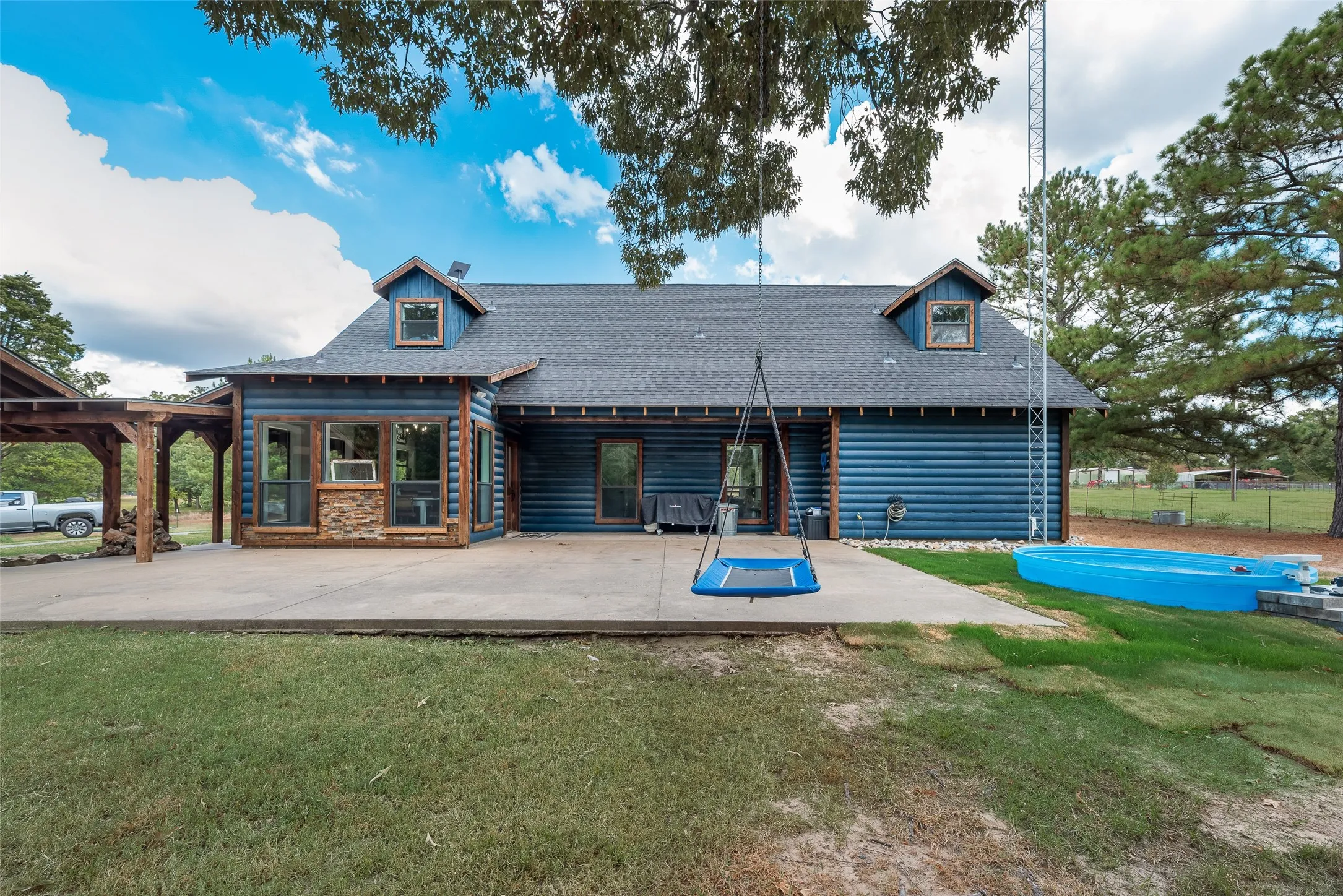 Rear of house with above ground pool, chicken coop, and covered parking