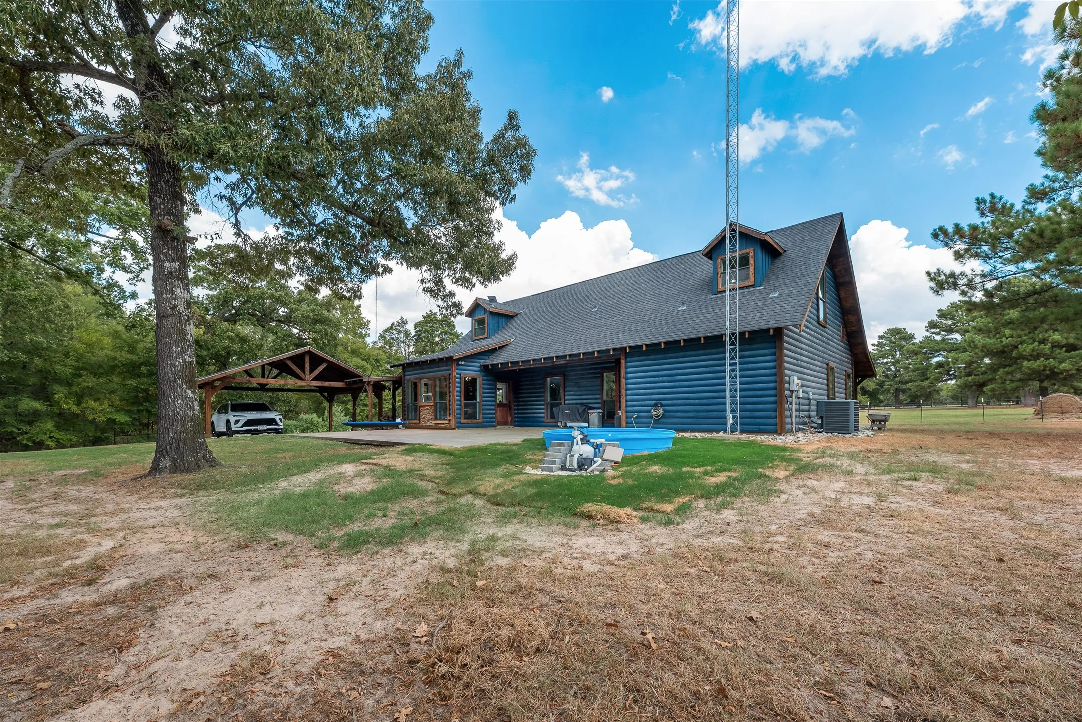 Rear of house with above ground pool, covered parking, and chicken coop