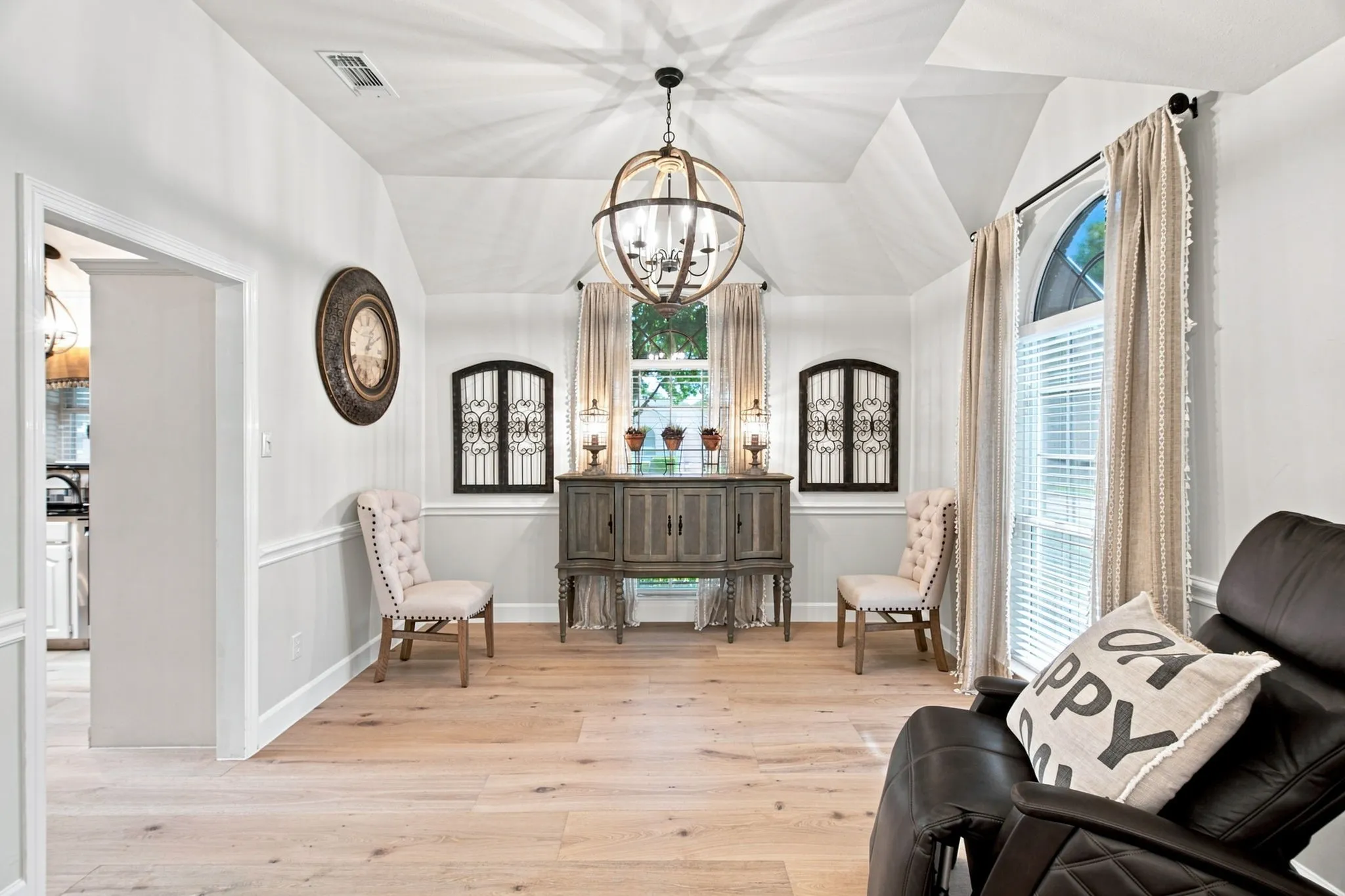 Vaulted ceiling, orb chandelier, wood-finish flooring, wainscoting, and arched window with blinds
