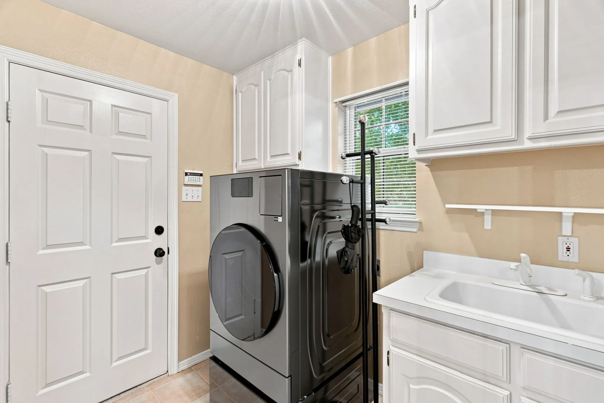 Laundry area featuring white cabinetry, a utility sink, and tile flooring