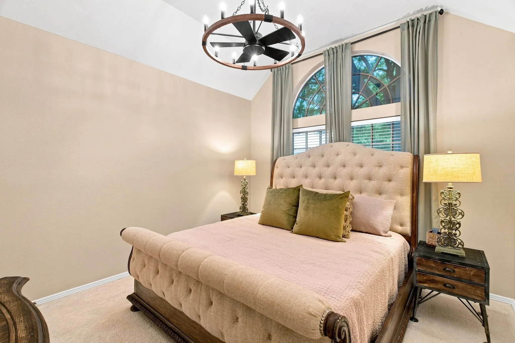 Vaulted ceiling with an overhead chandelier fan, arched windows, and light-toned wall finishes