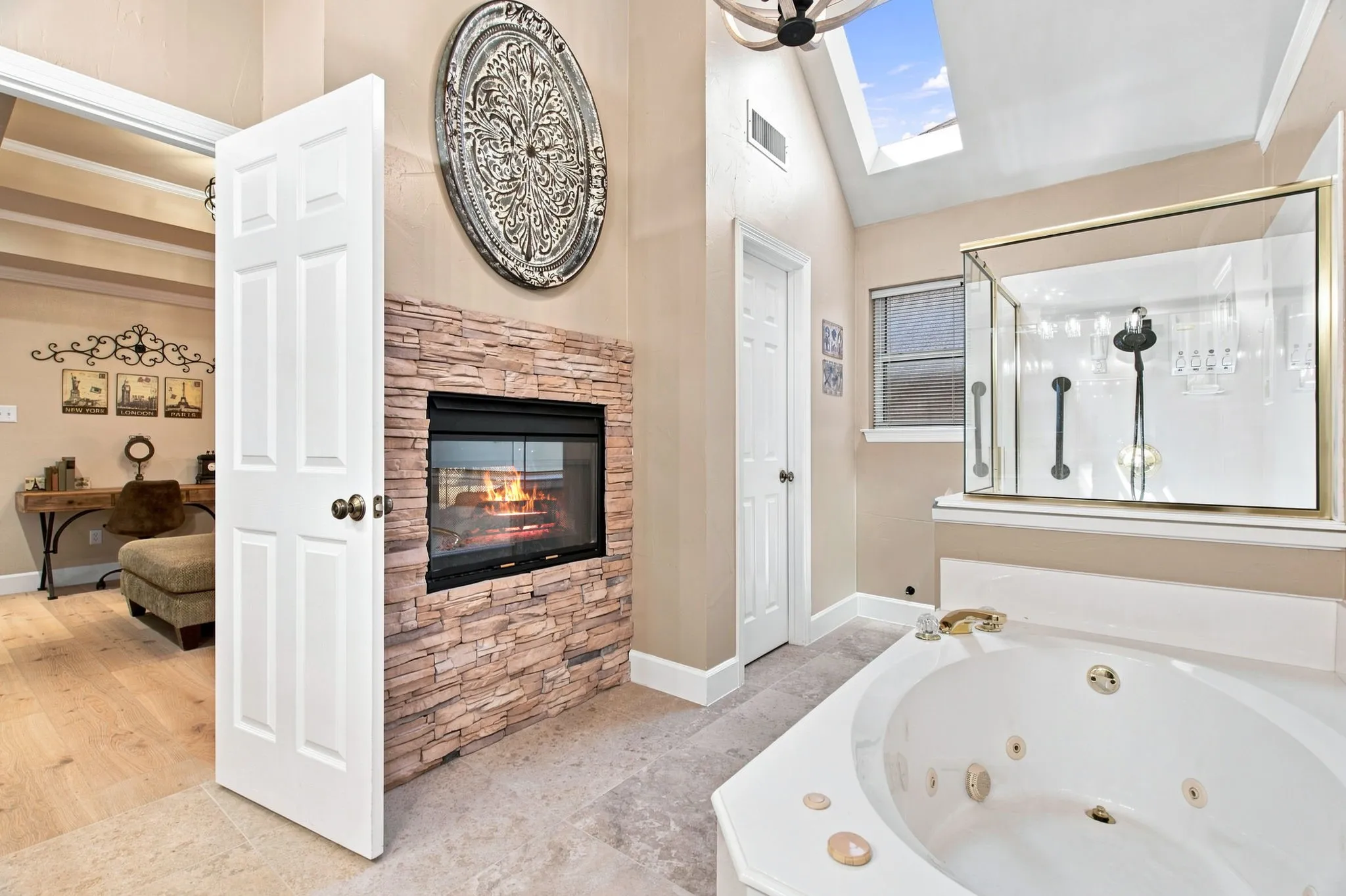 Built-in fireplace with a stacked stone facade, a corner jetted tub, and a glass-enclosed shower