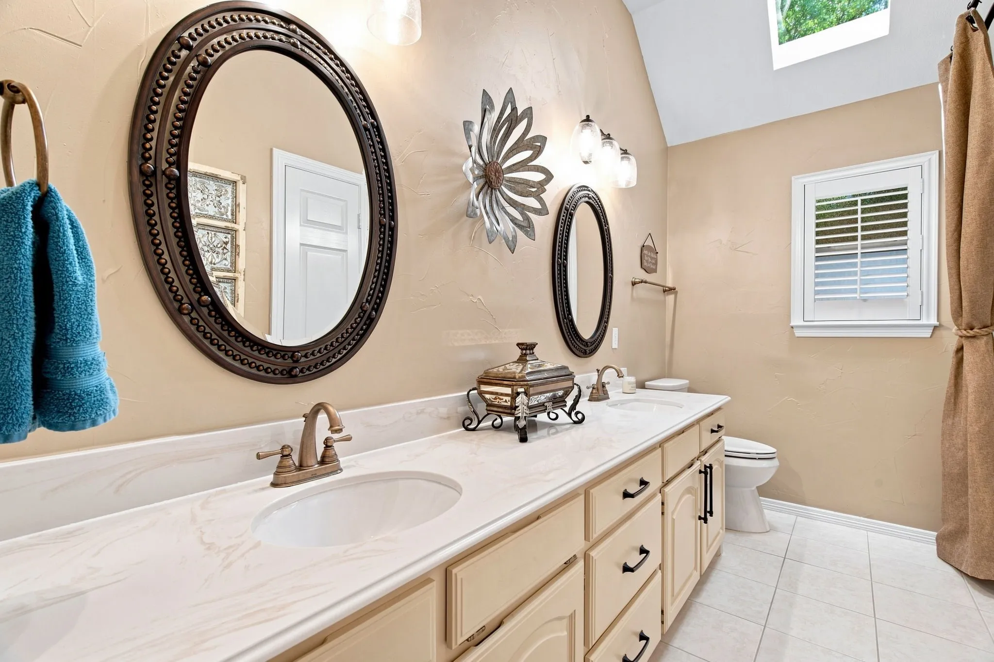 Dual vanity with integrated sinks, brushed bronze fixtures, and light-toned cabinetry