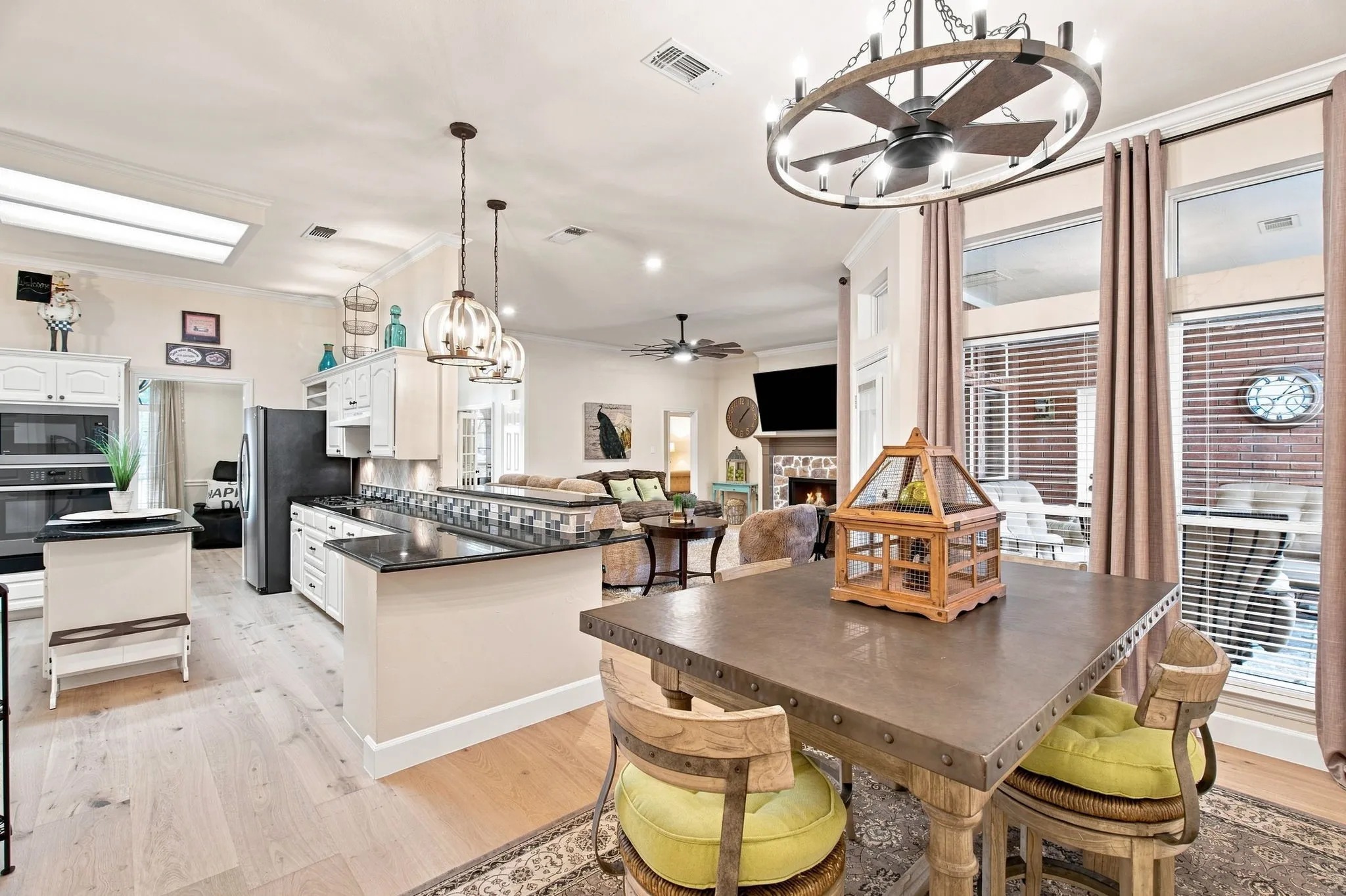Open-concept living space featuring wood-finish flooring, recessed lighting, and a large dining chandelier with a ceiling fan