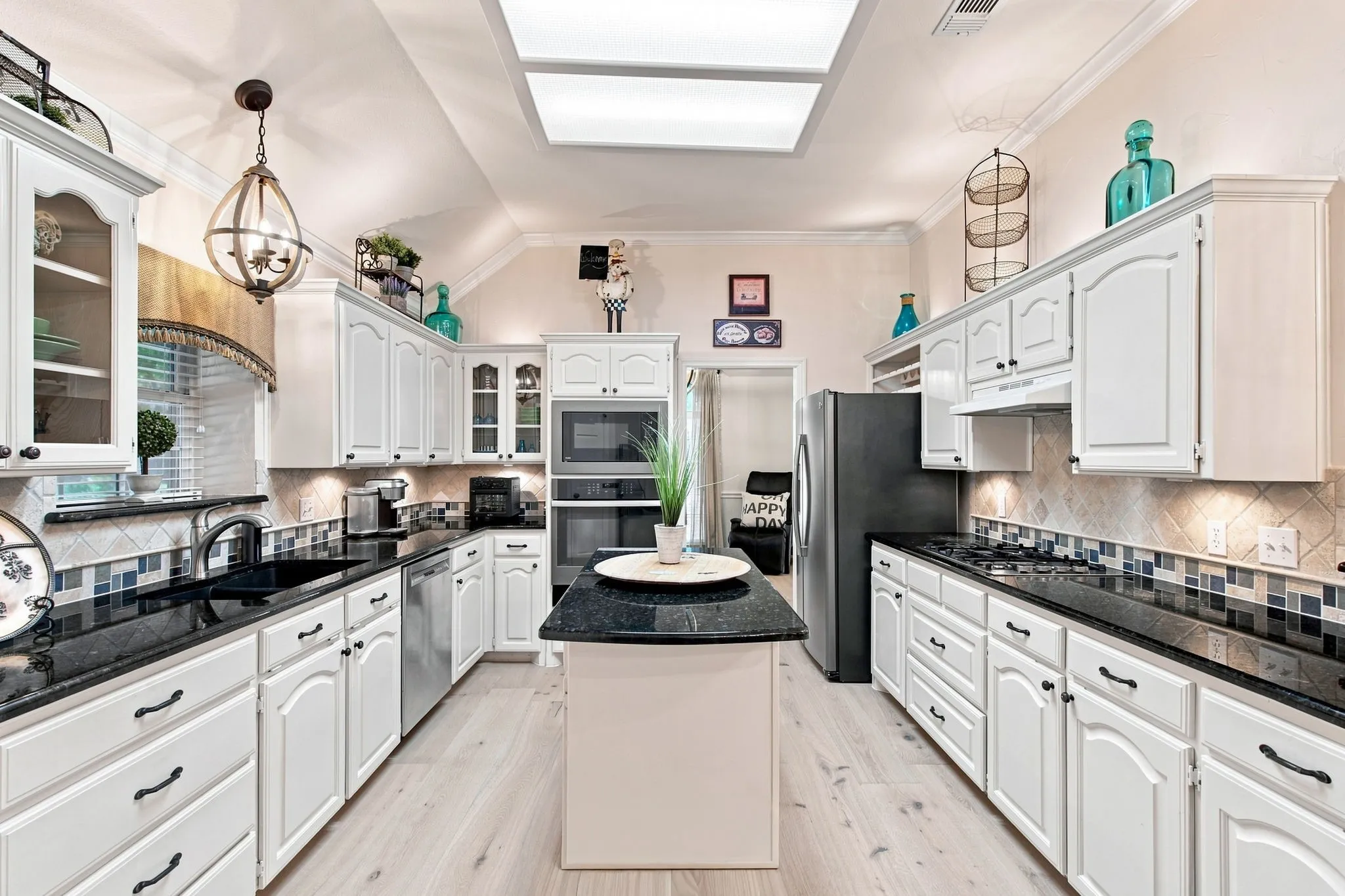 Spacious kitchen featuring white cabinetry, dark stone countertops, stainless steel appliances, and a central island