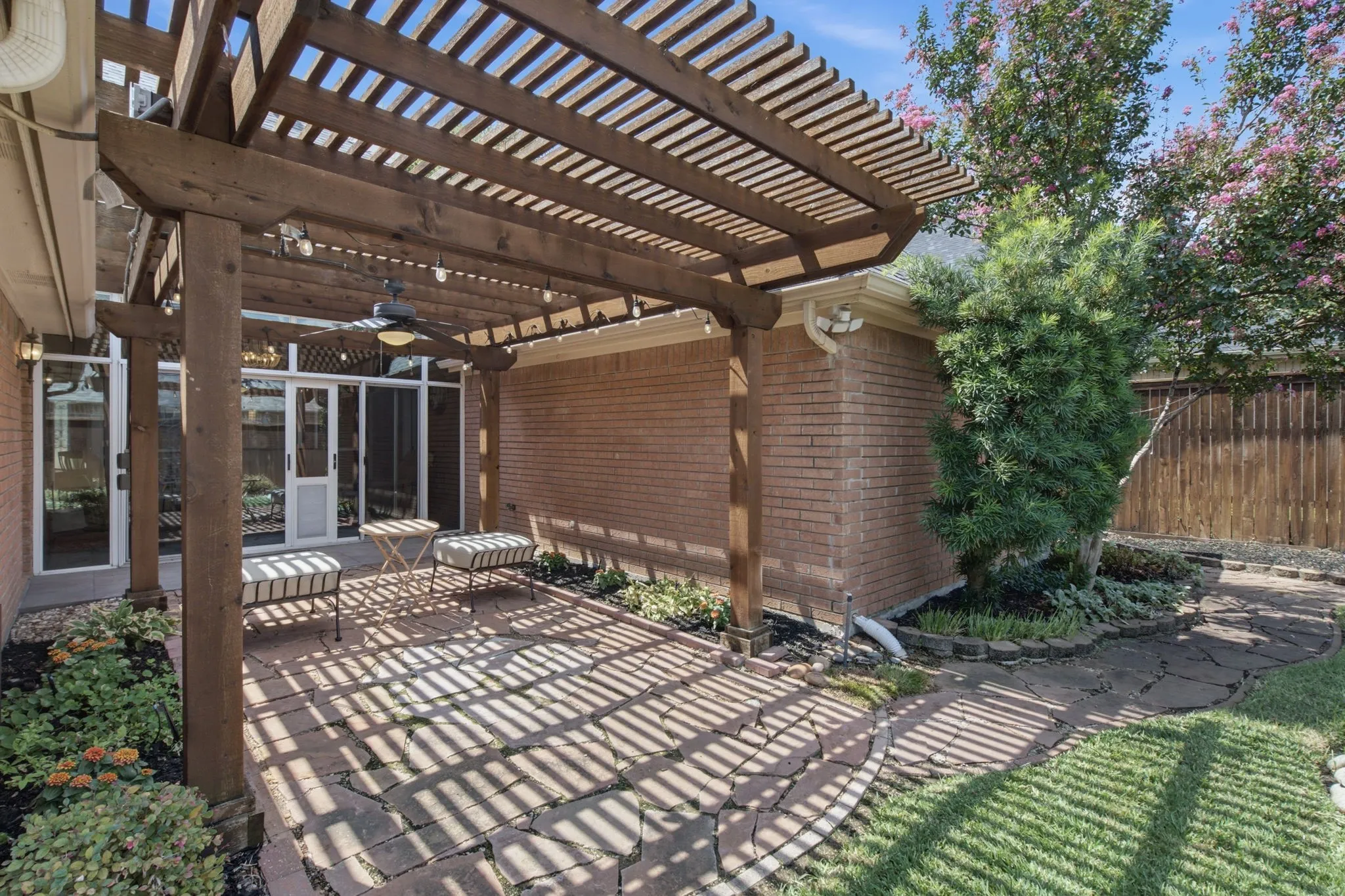 Wood pergola covering a paver patio with a ceiling fan