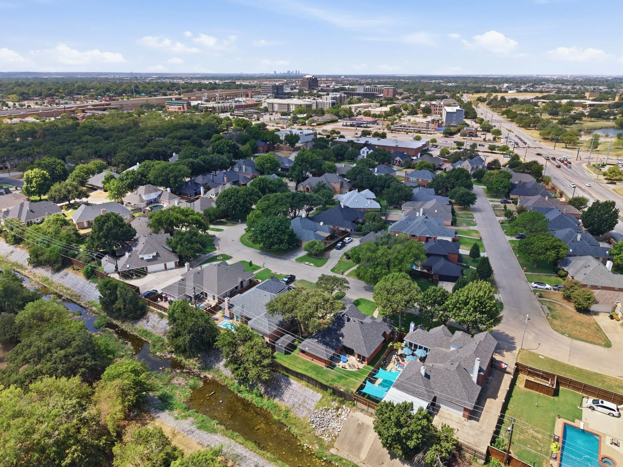 Residential neighborhood featuring mature trees, paved streets, and a prominent waterway
