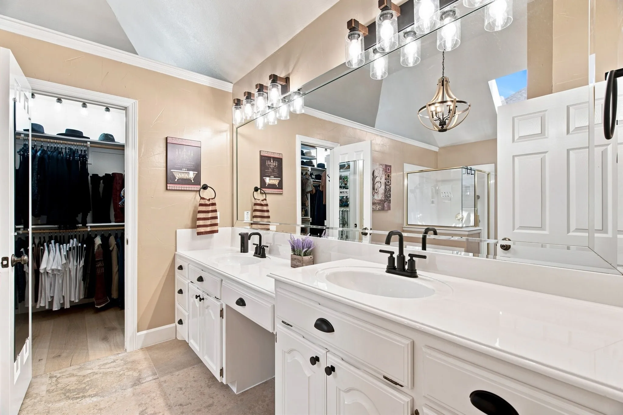 Dual vanity with white cabinetry, solid surface countertops, and dark fixtures