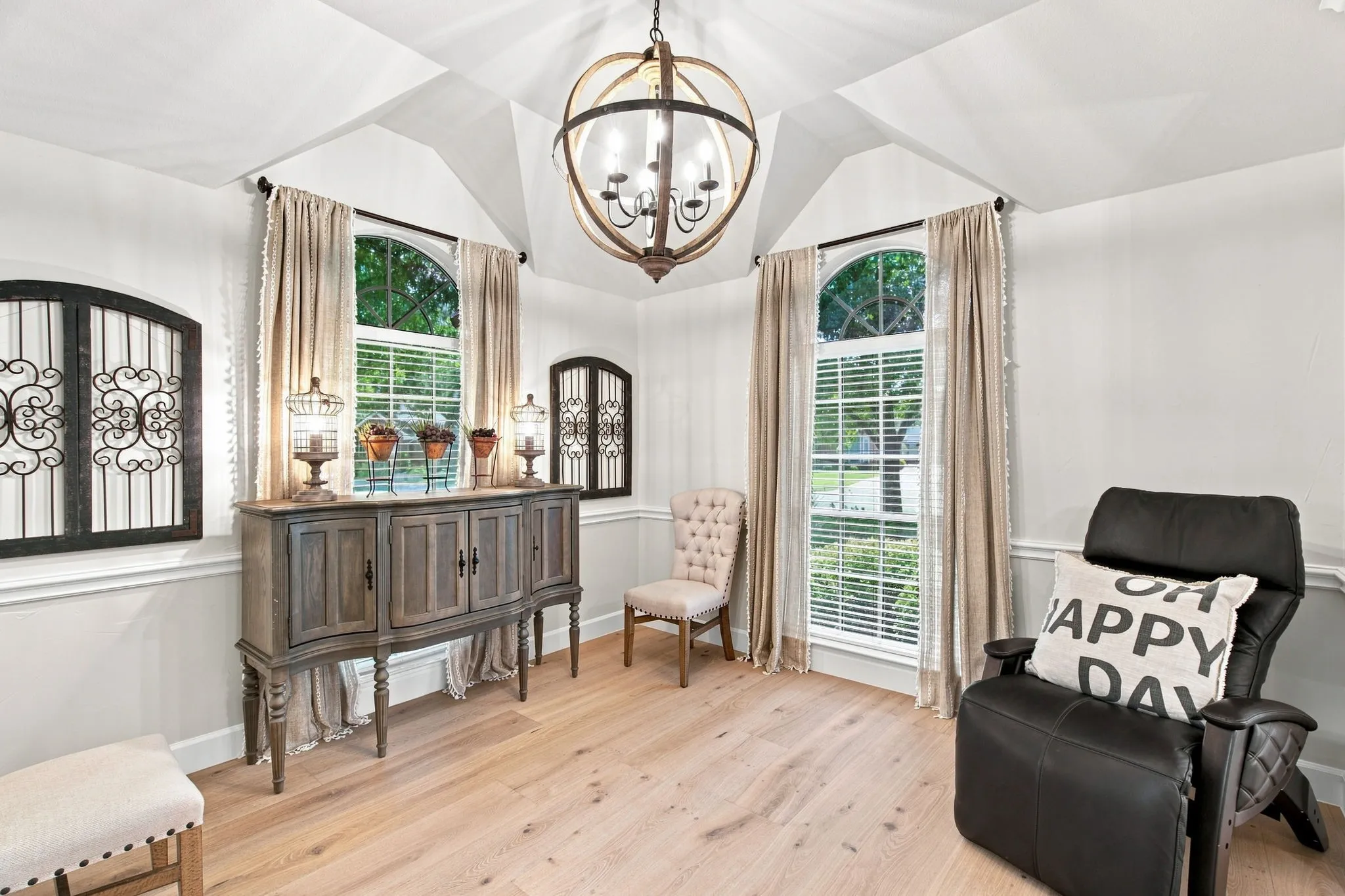 Vaulted ceiling with a spherical chandelier, wood-finish flooring, and arched windows with white blinds