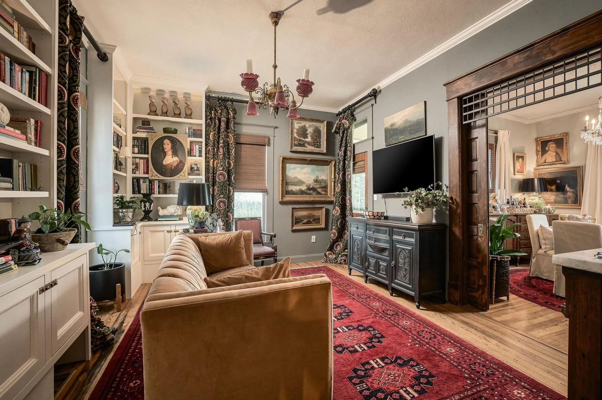 Cozy, elegant living room anchored by bespoke custom shelving, sophisticated draperies and timeless architectural details.
