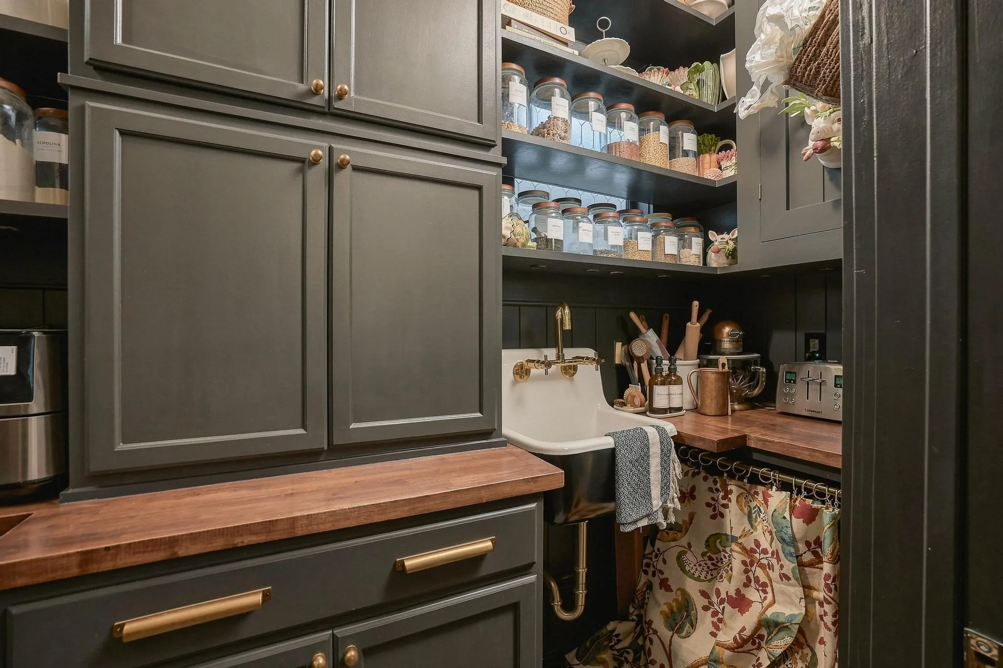 Inside the butler's pantry is floor-to-ceiling storage, a classic London sink, warm butcher-block counters and curated display shelving.