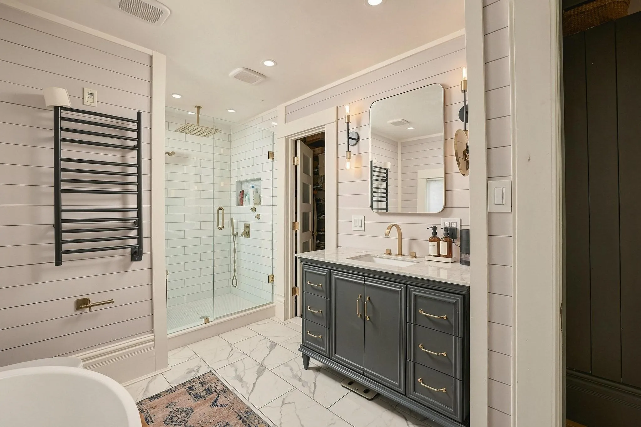 Floor-to-ceiling subway shower tile, frameless glass and vintage-style vanity with quartz top blend flawlessly.