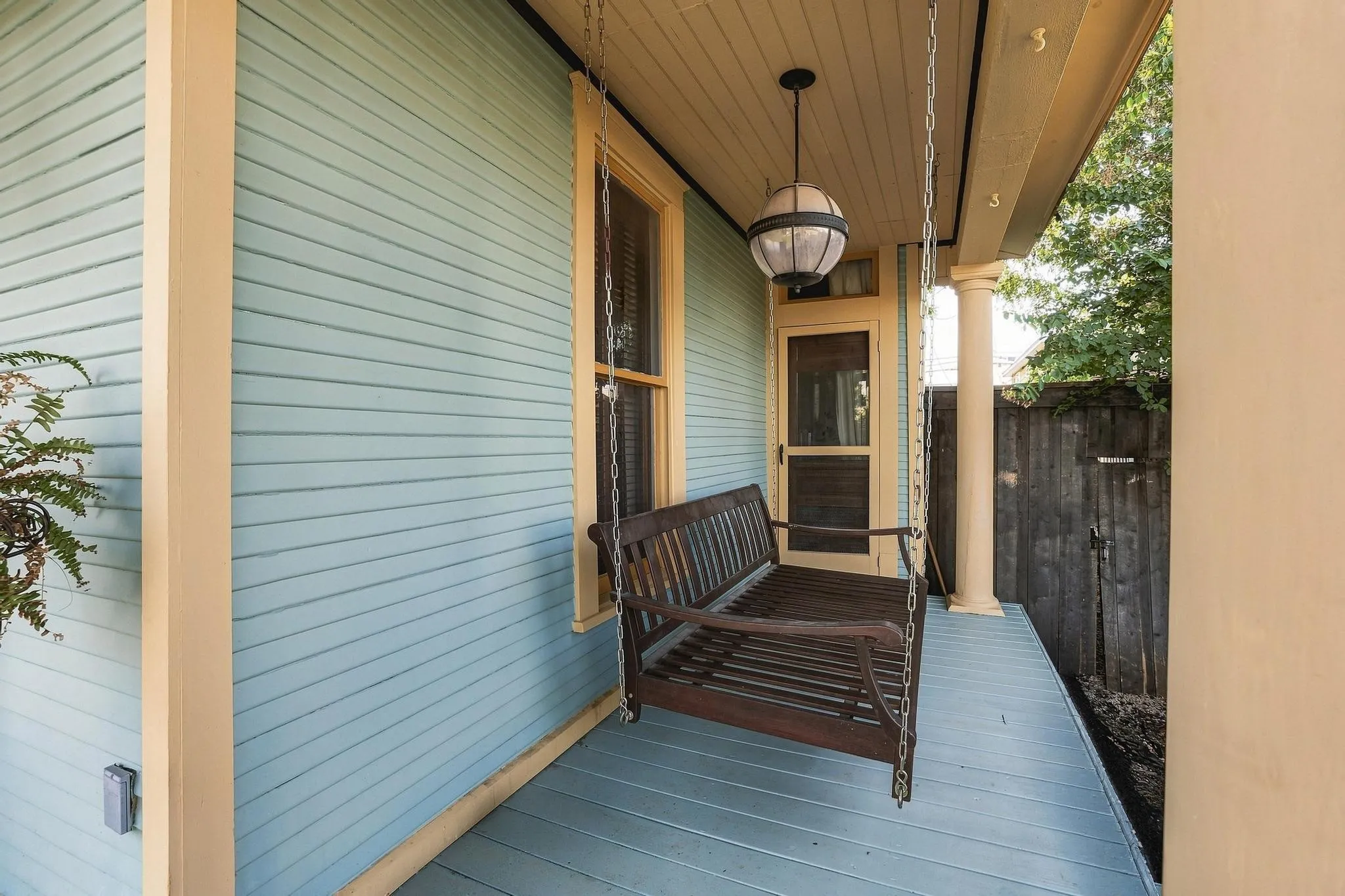 The Wrap-Around Porch with a Delightful Porch Swing and Side Door to the Living Room