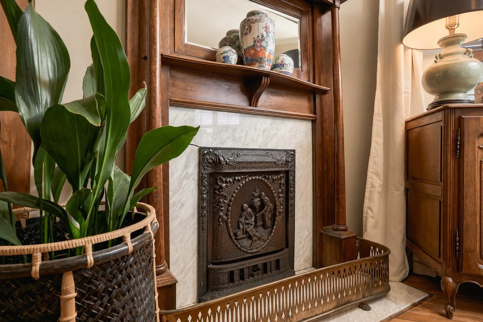 Victorian parlor fireplace with an intricate cast-iron insert, marble surround and majestic mirrored overmantel.