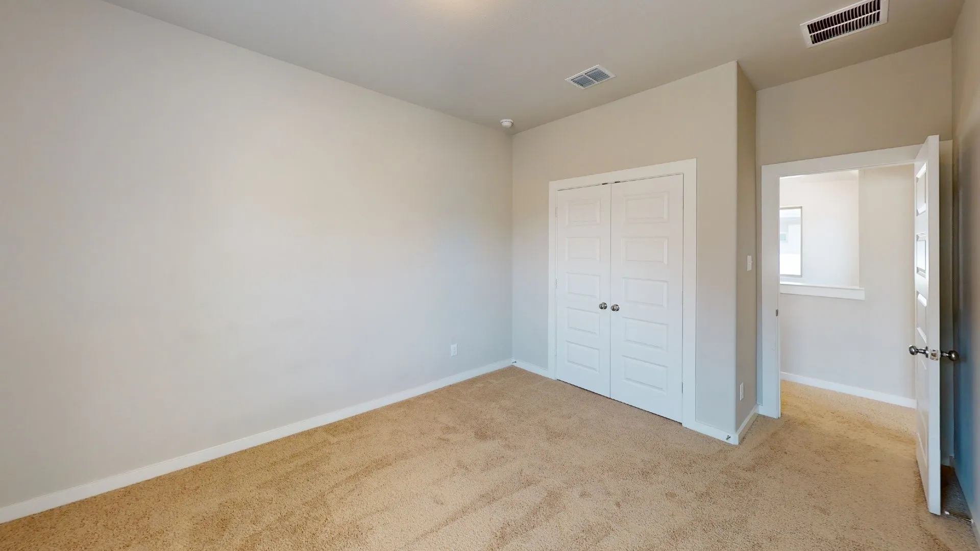 Neutral tone wall paint, light-colored carpeting, white paneled closet doors, interior door with hardware, and recessed ceiling lighting