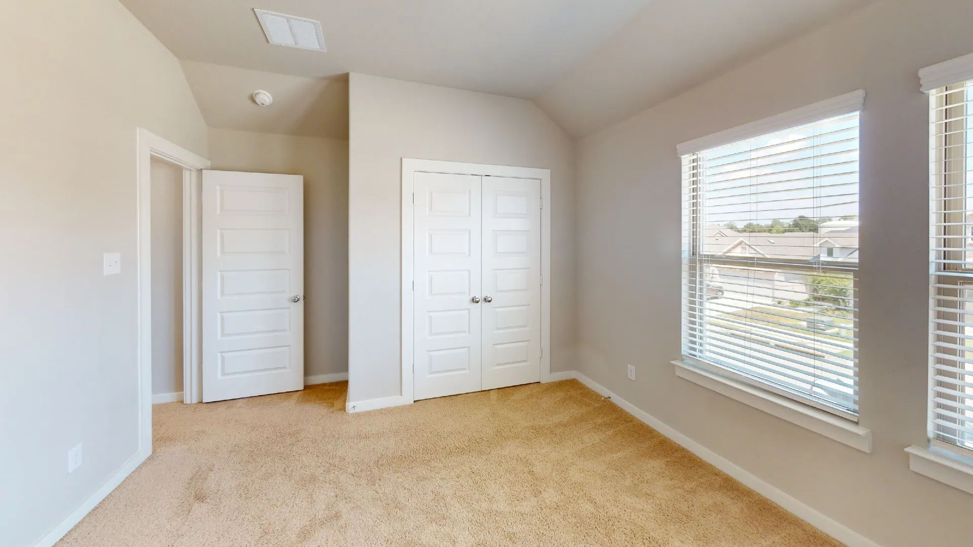 Neutral wall paint, plush carpet flooring, white trim, white panel doors, and window blinds