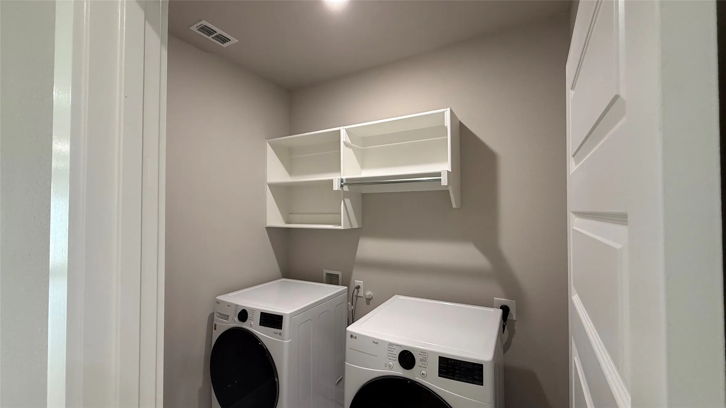 Laundry area with white cabinetry, shelving, and a hanging rod
