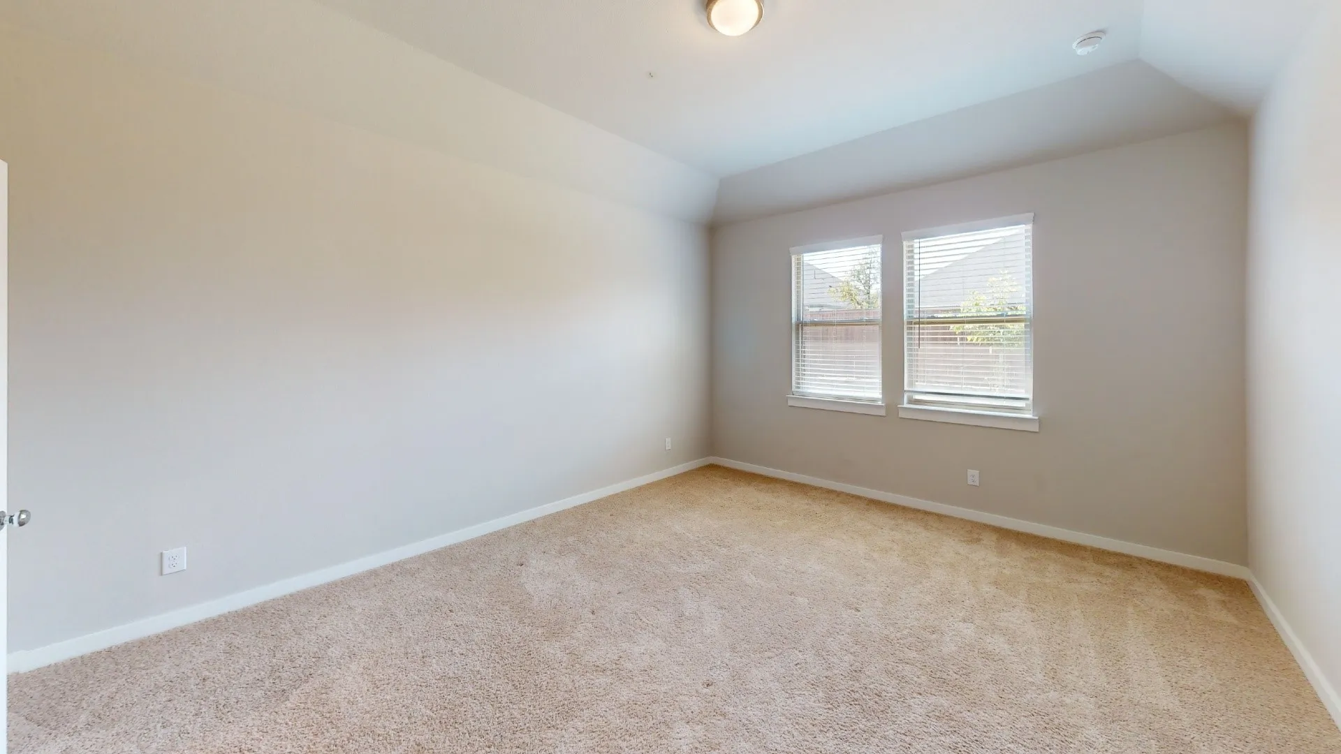 Carpeted flooring, vaulted ceiling, and two windows with blinds
