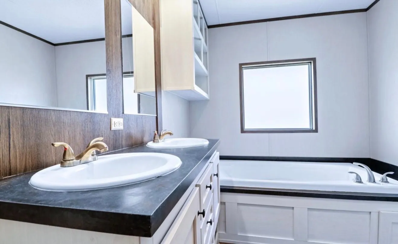Dual vanity with undermount sinks and gold-finish fixtures, wood-look paneling, and an integrated bathtub