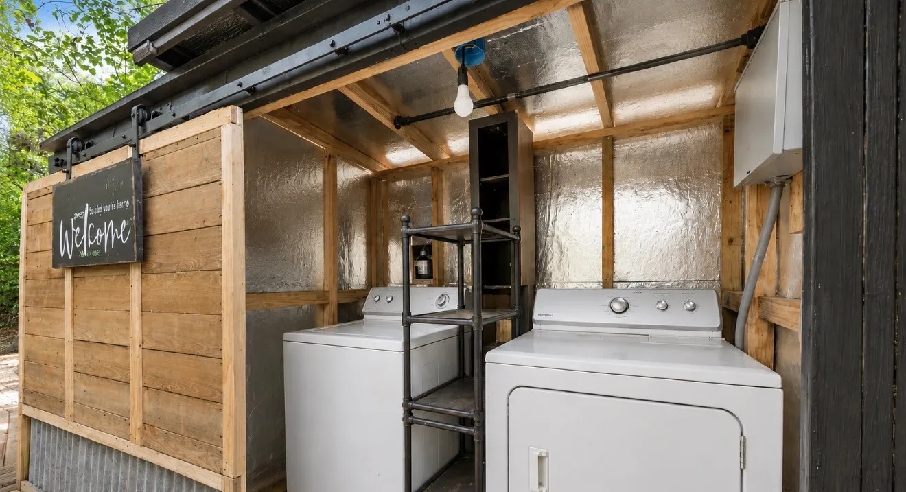 Enclosed utility space featuring a corrugated metal base, wood slat siding, and a barn door mechanism