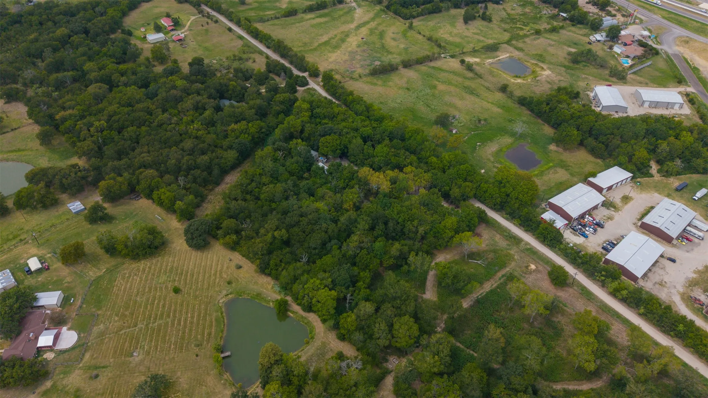 Wooded acreage featuring multiple ponds, open fields, and various outbuildings