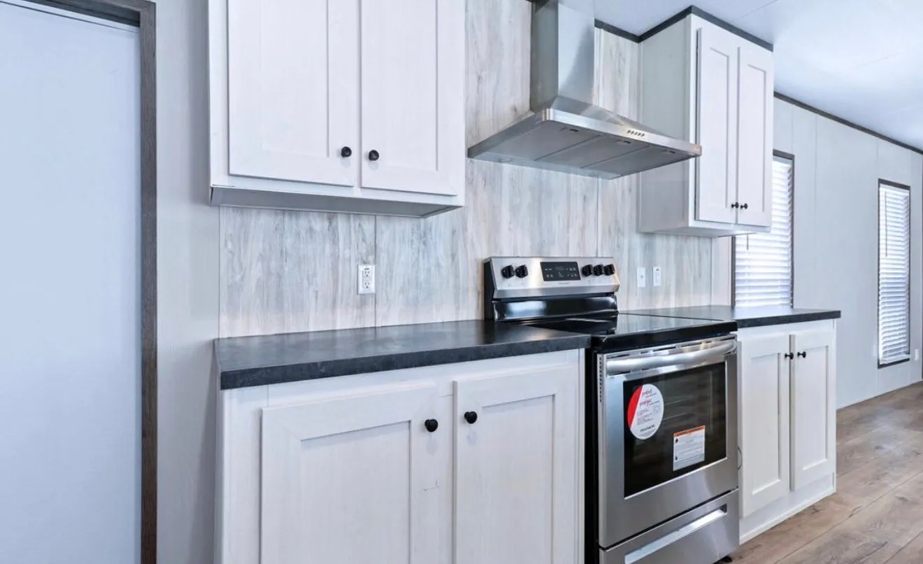 White shaker-style cabinetry with black hardware, dark countertops, stainless steel range and hood, and wood-finish flooring