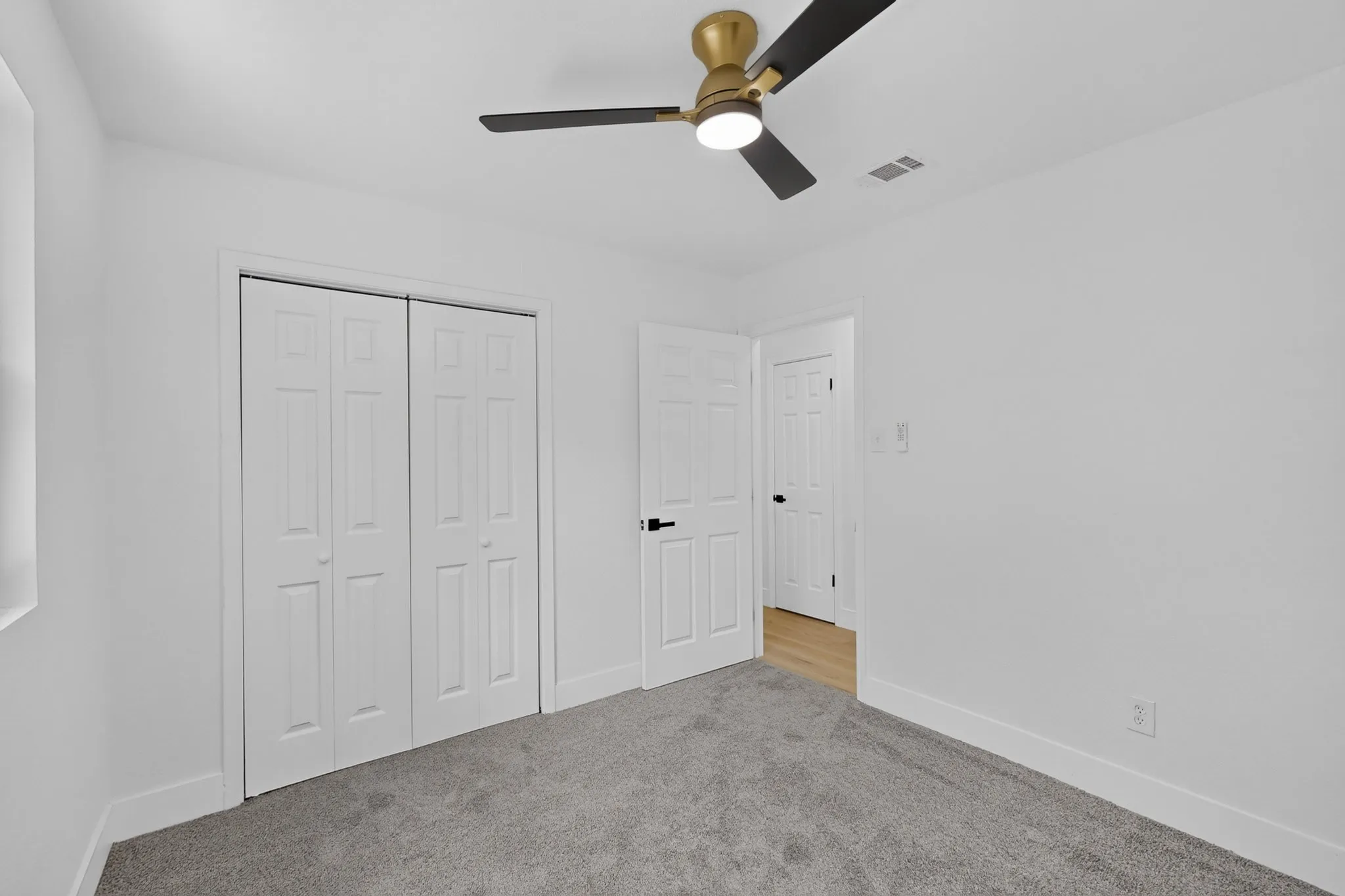Plush carpeting, a ceiling fan with integrated lighting, and a bi-fold closet door