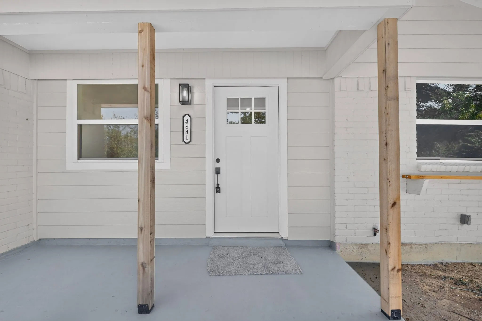 Front porch with a white paneled entry door, transom windows, and an exterior wall light fixture