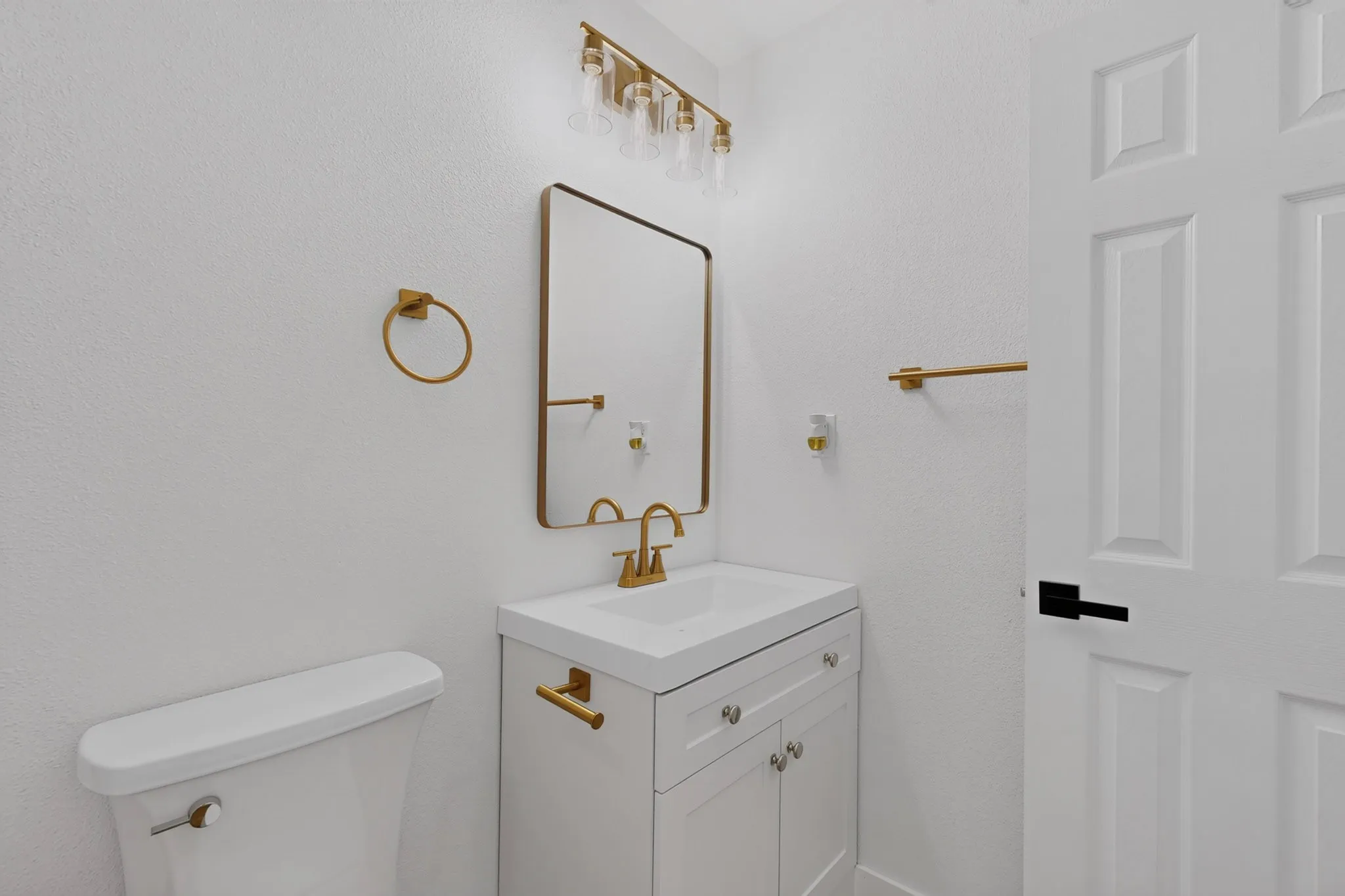 Bathroom featuring a white vanity with gold-finish hardware, gold-finish faucet, and a rectangular framed mirror