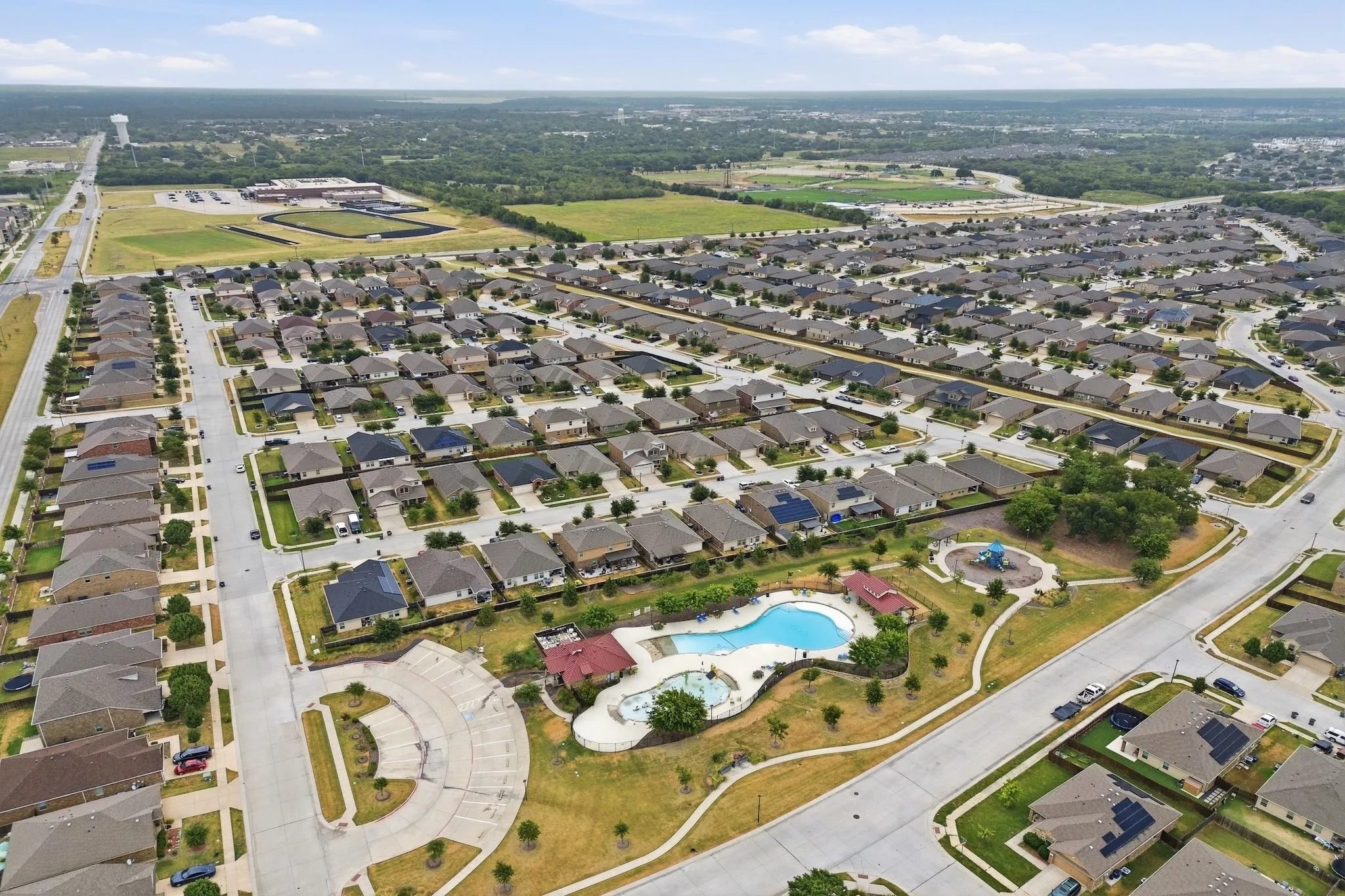 Expansive residential development featuring numerous single-story homes, a community pool, and a dedicated playground area