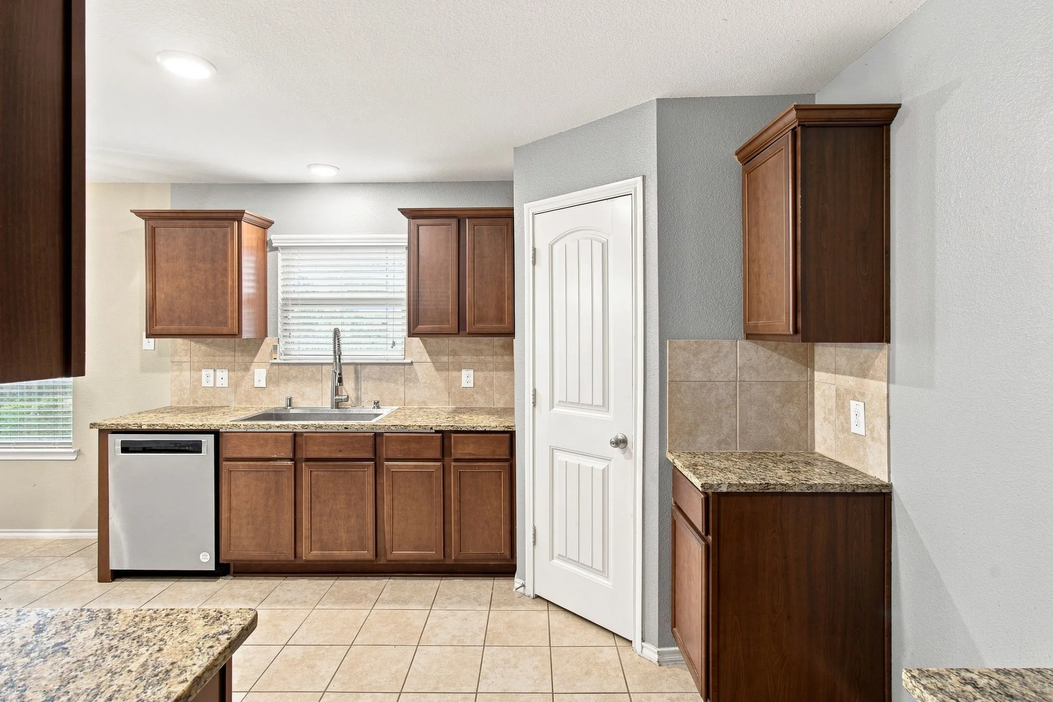Kitchen featuring wood cabinetry, light-toned tile flooring, recessed lighting, and stone countertops