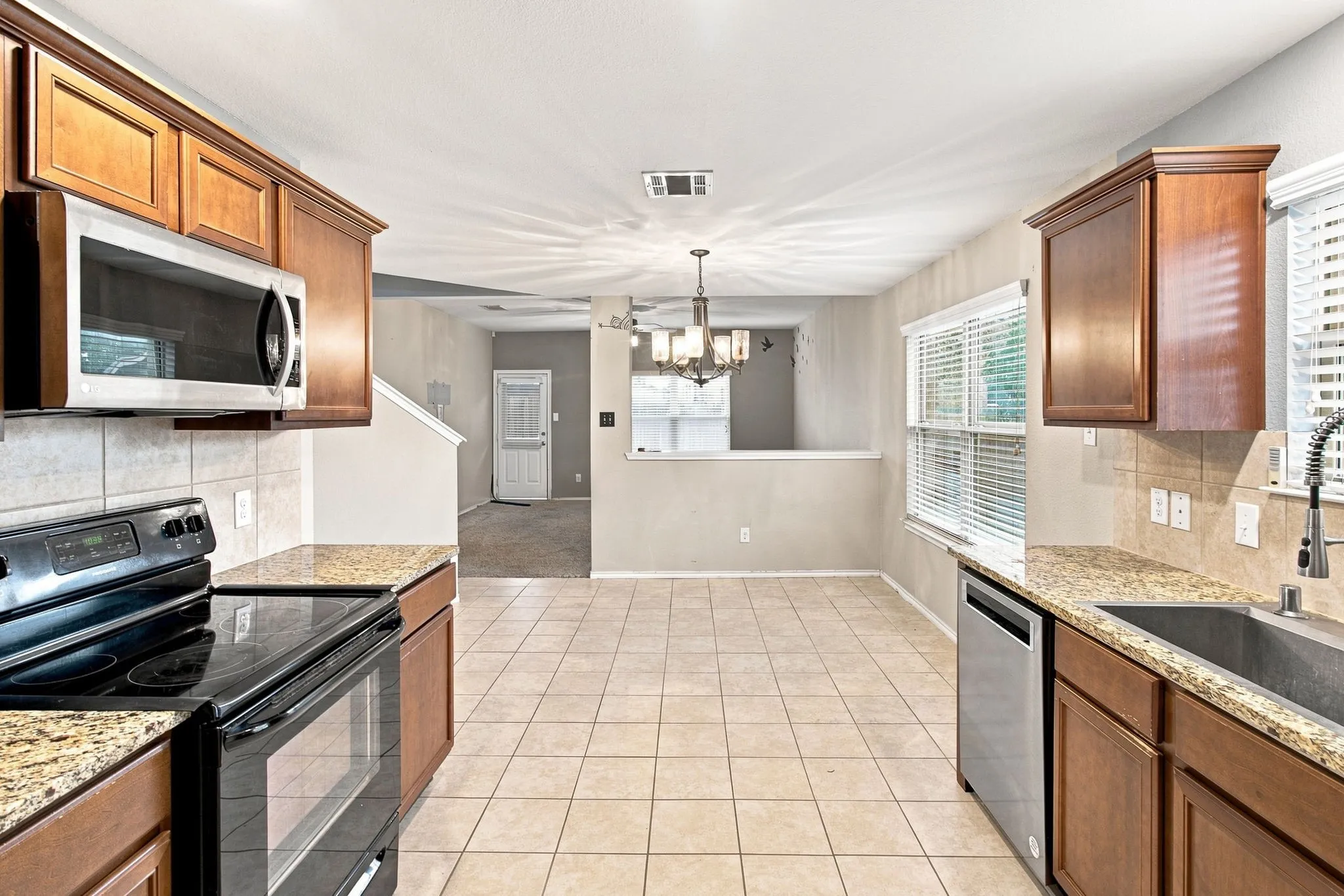 Kitchen featuring wood-finish cabinetry, stainless steel appliances, tiled flooring, and light-toned countertops