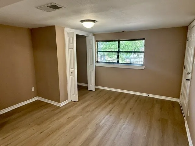 Neutral wall tones, wood-finish flooring, and a flush mount ceiling light