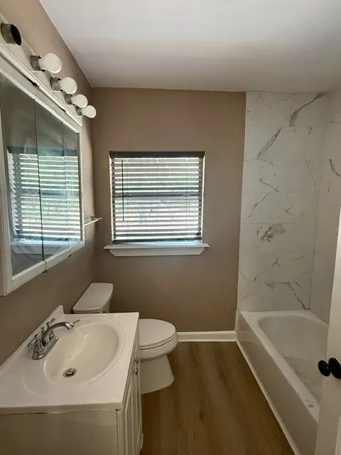 Bathroom featuring a white vanity with integrated sink, chrome faucet, and wood-finish flooring