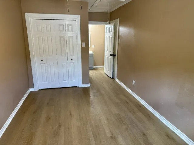 Wood-finish flooring, neutral wall color, white trim, and a bi-fold closet
