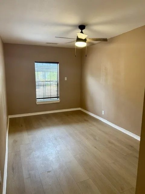 Wood-finish flooring, ceiling fan with integrated lighting, window with blinds, and neutral wall tones