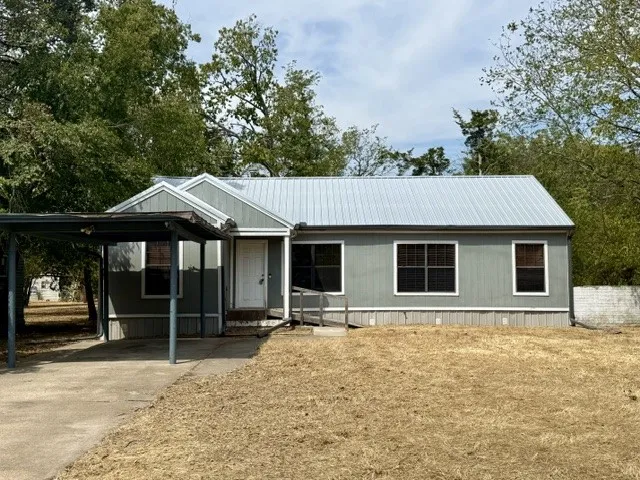 Single-story residence featuring a metal roof, light-toned siding, and a covered carport