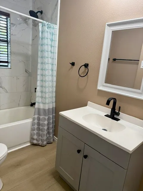 Bathroom featuring a vanity with an integrated sink, black fixtures, and a shower-over-tub with tile surround