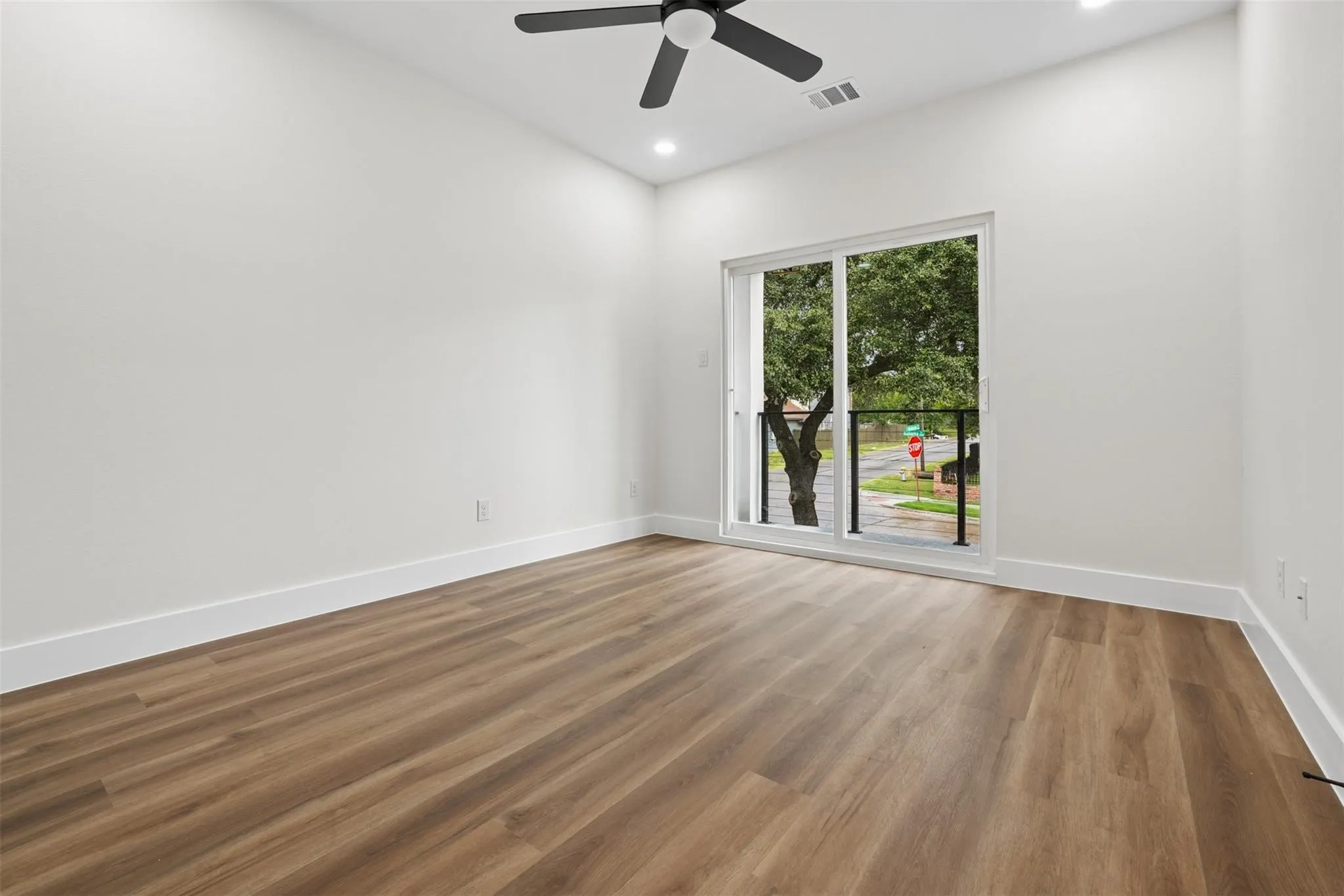 Vaulted ceiling with a ceiling fan, recessed lighting, wood-finish flooring, and a sliding glass door