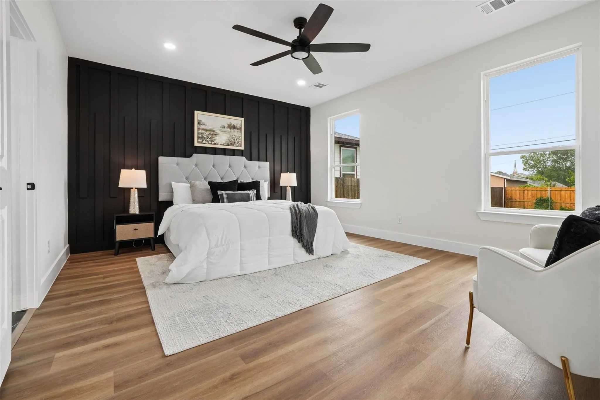 Accent wall with vertical paneling, wood-finish flooring, recessed lighting, ceiling fan, and multiple windows